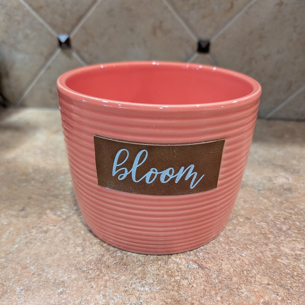 Coral planter with 'bloom' text